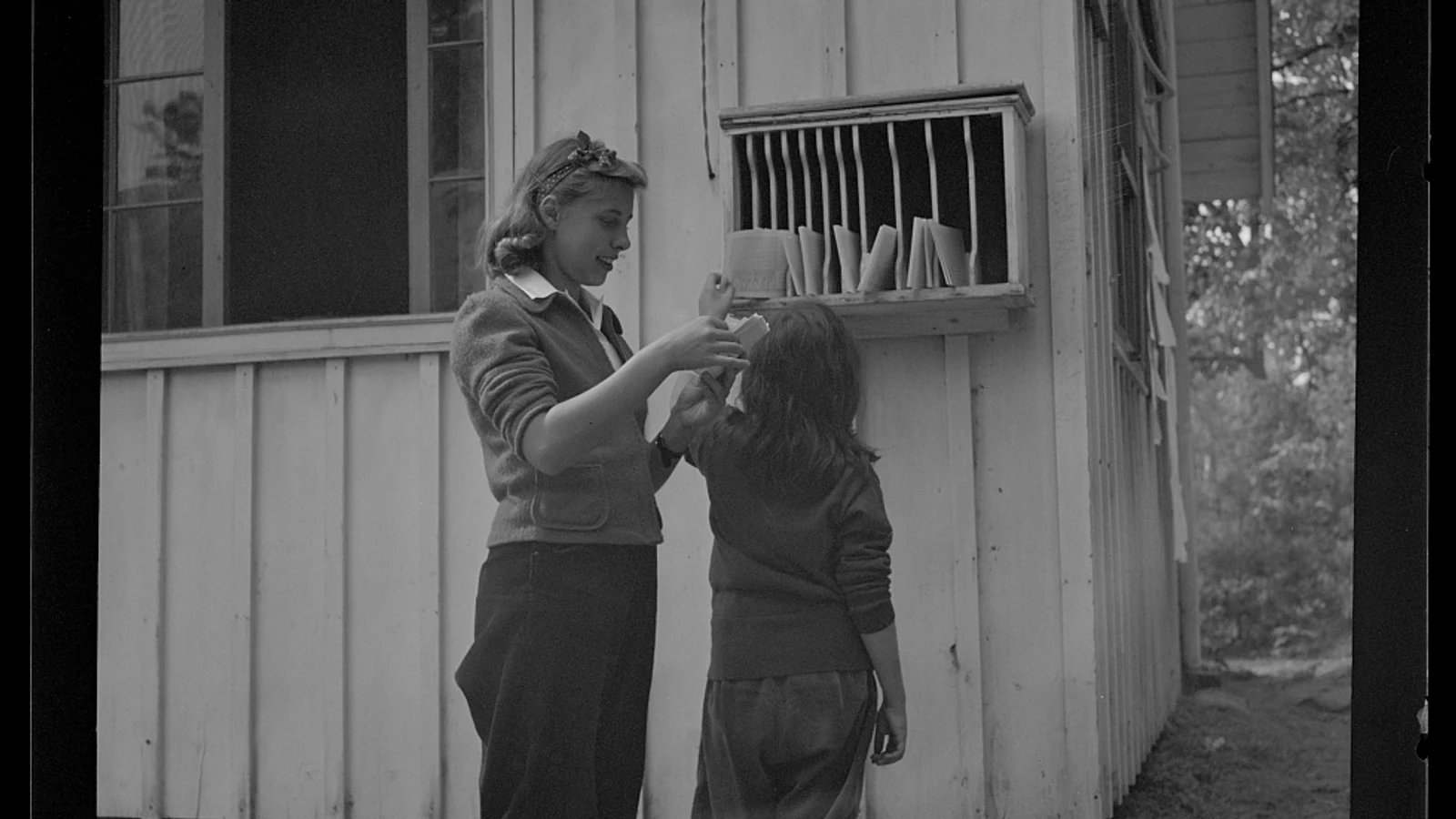 National Music Camp students reading letters at the camp mailboxes in Interlochen in 1942.