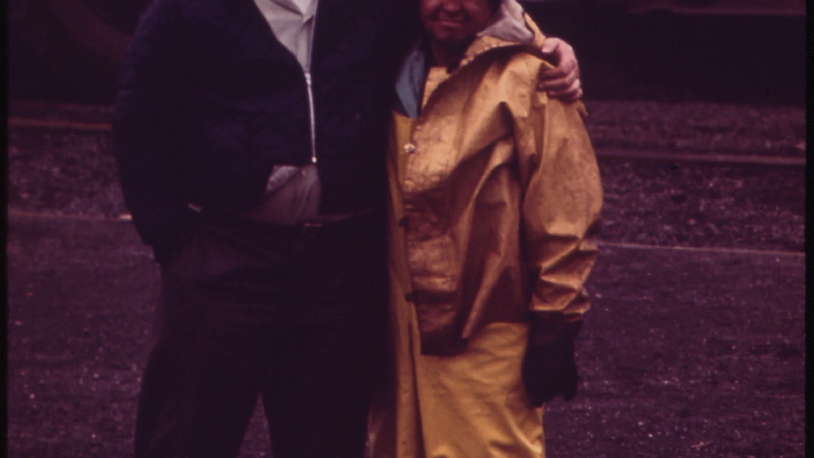 Two steelworkers in hard hats stand together inside an Inland Steel plant.