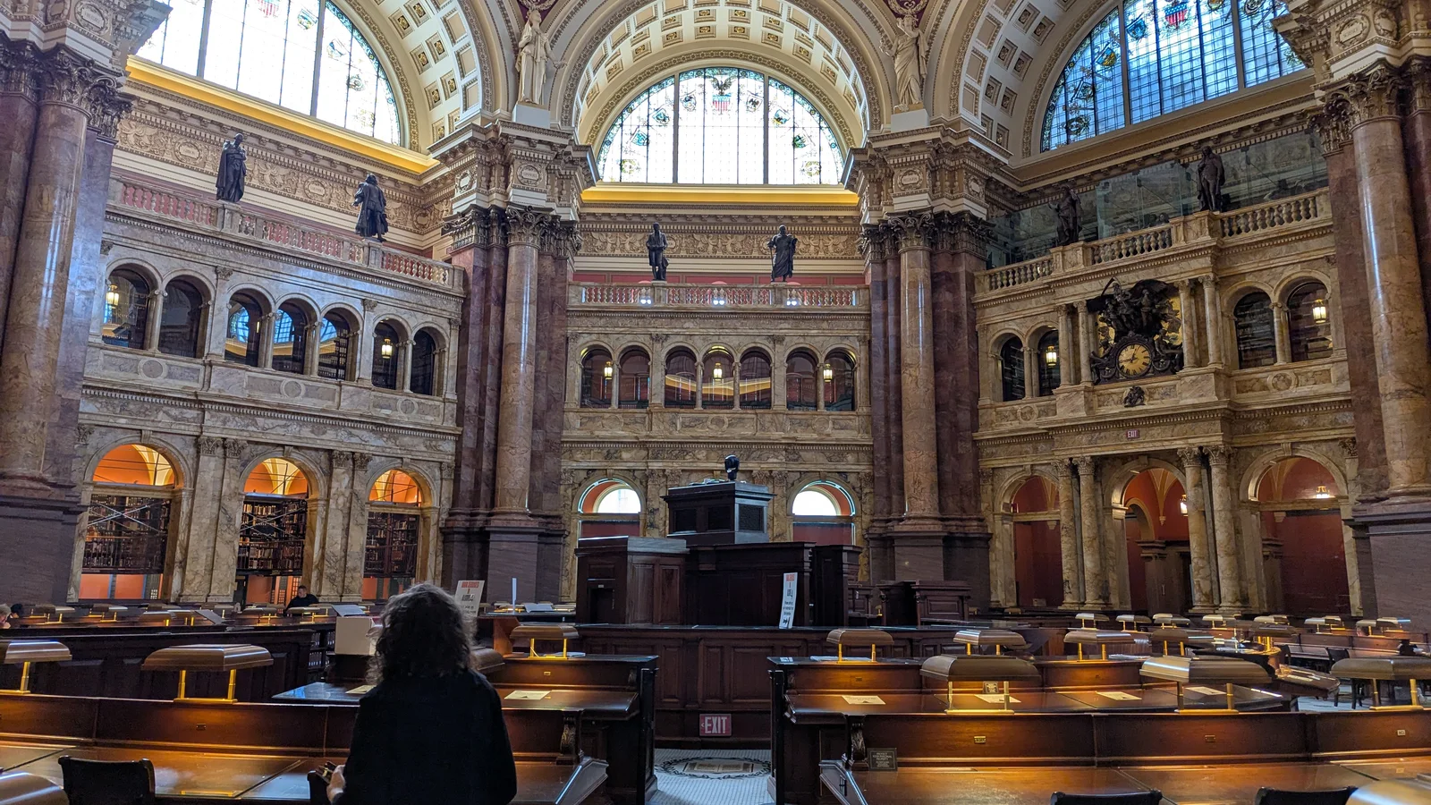 Ground-level view across desks and columns in the Library of Congress Main Reading Room.