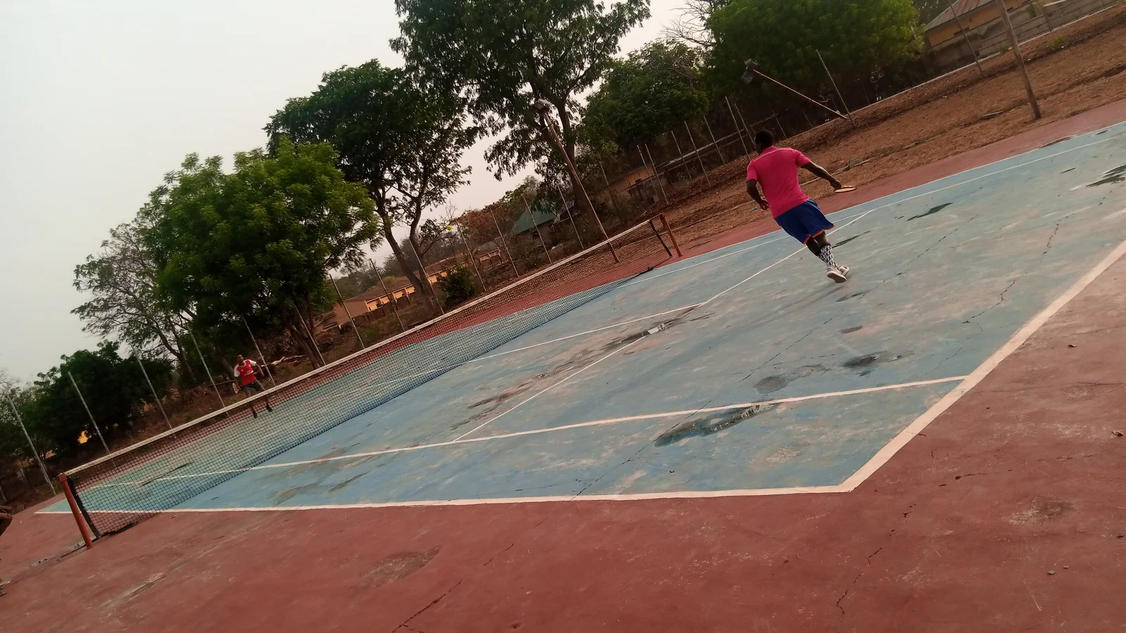 Two tennis players move across opposite sides of a blue outdoor court during a rally.