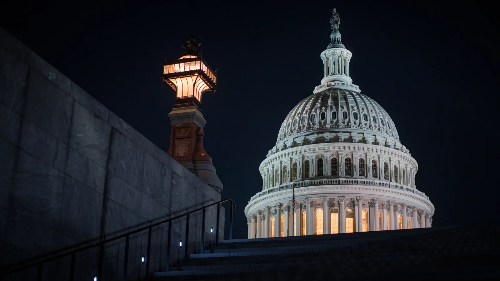 The illuminated U.S. Capitol dome rises above the grounds at night.
