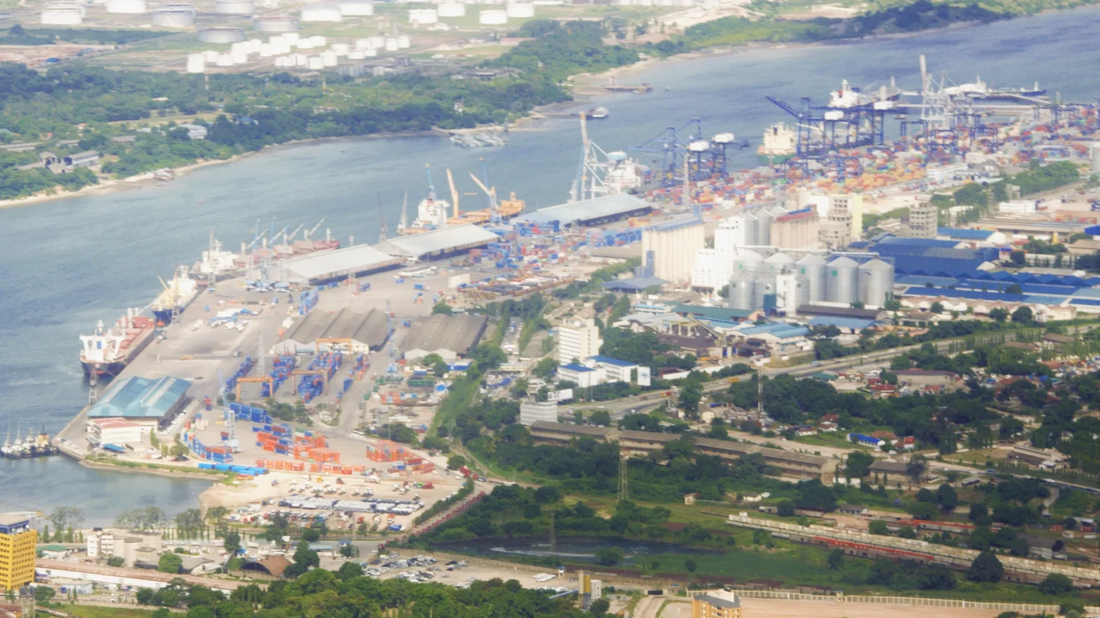 Cargo ships, cranes and waterfront facilities fill a wide view of Dar es Salaam port.