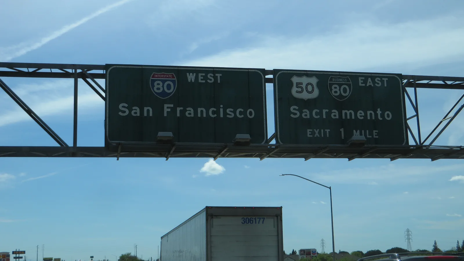 Dense freeway traffic fills multiple lanes beneath signs and overpasses in West Sacramento.