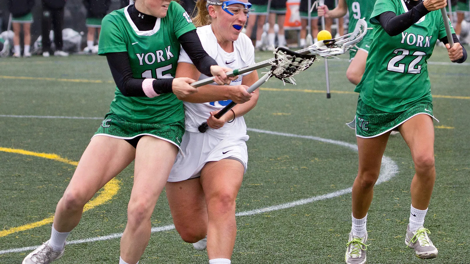 Women’s college lacrosse players contest the ball during a match.
